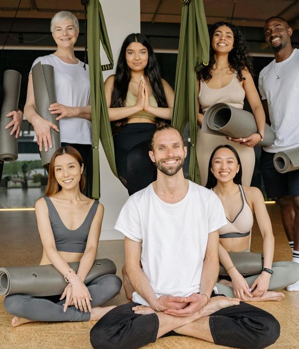 Diverse group of people smiling and preparing for a yoga class.