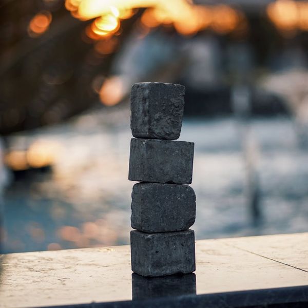 Stack of smooth zen stones near a calm water surface.